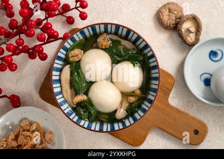 Essen Sie große Tangyuan Yuanxiao, Tang Yuan, klebrige Reisknödelbällchen, mit herzhafter Gemüsesuppe in einer Schüssel für das Wintersonnenfest. Stockfoto