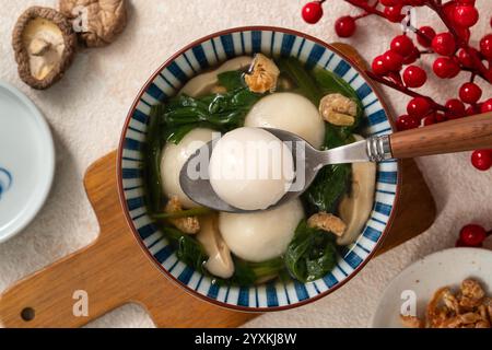 Essen Sie große Tangyuan Yuanxiao, Tang Yuan, klebrige Reisknödelbällchen, mit herzhafter Gemüsesuppe in einer Schüssel für das Wintersonnenfest. Stockfoto