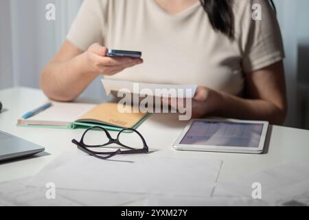 Frau, die Rechnungen online mit dem Smartphone zu Hause bezahlt. Rechnungszahlungskonzept. Digitale Zahlung über Internet-Banking und qr-Code Stockfoto