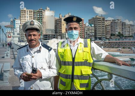 Zwei ägyptische Polizeibeamte stehen auf Alexandrias Stanley Bridge mit Blick auf das Mittelmeer und die Stadt, Sicherheit und das städtische Leben in Ägypten. Stockfoto