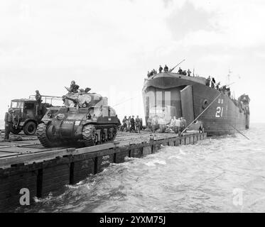 Die USS LST-21 entlädt Panzer und LKW der britischen Armee in den frühen Morgenstunden der Invasion am Gold Beach am 6. Juni 1944 auf einen „Rhino“-Lastkahn. Beachten Sie den Spitznamen „Virgin“ auf dem „Sherman“-Tank auf der linken Seite - Foto der US-Küstenwache Stockfoto