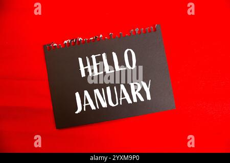 Hallo januar Nachricht auf schwarzem Papier mit rotem Hintergrund. Konzeptionelles Hallo januar-Symbol. Kopierbereich. Stockfoto