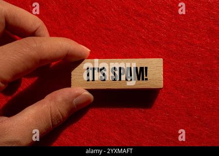 Es ist eine Spam-Nachricht auf Holzblock mit rotem Hintergrund. Konzeptionell ist das Spam-Symbol. Kopierbereich. Stockfoto