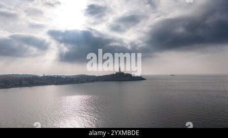 Ein atemberaubender Blick aus der Luft auf die historische Stadt Rovinj, Kroatien, umgeben von der Adria unter einem dramatischen bewölkten Himmel. Stockfoto