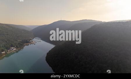 Eine ruhige Luftaufnahme der Bucht von Lim in Istrien, Kroatien, eingerahmt von sanften Hügeln, die in sanftes Sonnenlicht getaucht sind. Das reflektierende blaue Wasser und die natürliche Landschaft Stockfoto