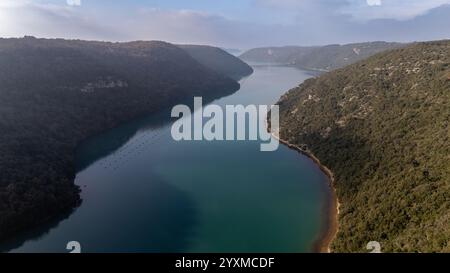 Ein atemberaubender Blick aus der Luft auf die Bucht von Lim in Istrien, Kroatien, mit seinem ruhigen blauen Wasser, das von üppigen grünen Hügeln und zerklüfteten Klippen flankiert wird. Stockfoto