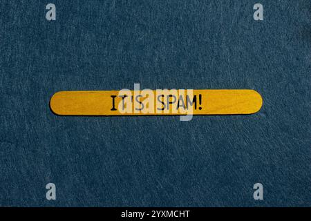 Es ist eine Spam-Nachricht auf gelbem Holzstab mit grauem Hintergrund. Konzeptionell ist das Spam-Symbol. Kopierbereich. Stockfoto