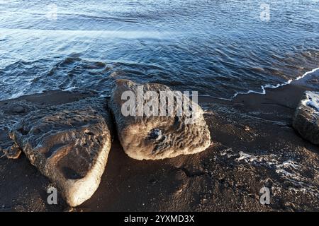 Schmelzende Eisschollen mit Sand lagen an der Ostseeküste, natürlicher Wintergrund Stockfoto