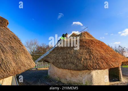 Nachbildungen neolithischer Häuser, die vor dem Stonehenge Besucherzentrum in der Salisbury Plain, einem geplanten antiken Monument, in Wiltshire, England, reetgedeckt werden Stockfoto