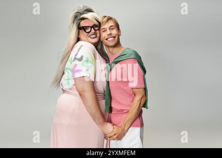 Zwei Personen umarmen und lächeln, zeigen ihren lebendigen Stil und feiern queere Identität. Stockfoto