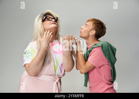 Zwei queere Individuen zeigen Freude und Kreativität durch spielerische Interaktionen und mutige Mode. Stockfoto
