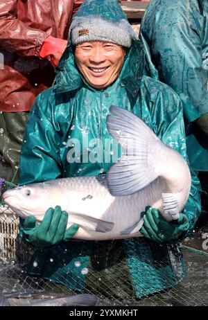 Huzhou, chinesische Provinz Zhejiang. Dezember 2024. Ein Dorfbewohner zeigt einen Fisch, der im Dorf Dongheng in der Stadt Luoshe, Bezirk Deqing, Stadt Huzhou, ostchinesische Provinz Zhejiang, 17. Dezember 2024 gefangen wurde. Die Dorfbewohner hier nutzen die laufende Winterfischsaison, um den Markt mit frischen Fischernten zu versorgen. Quelle: Xie Shangguo/Xinhua/Alamy Live News Stockfoto