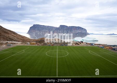 Uummannaq Football Field, nordwestlich von Grönland, auf einer Insel. Eisberge im Uummannaq-Fjord. Große Berge und Gletscher im Hintergrund. Stockfoto