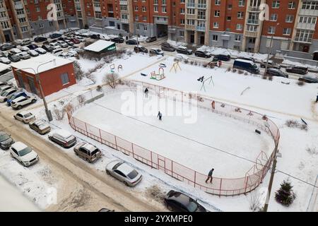 Eine wunderschöne Winterszene mit einer Eisbahn, umgeben von bezaubernden, verschneiten Apartments Stockfoto