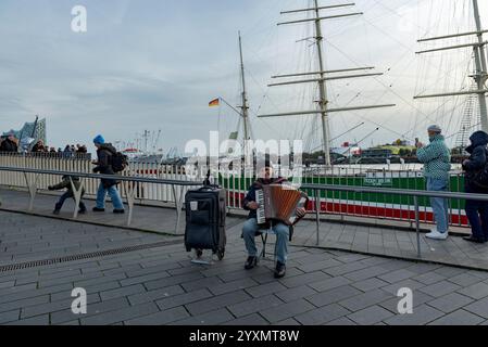 Ein Mann spielt Akkordeon im Stadthafen / hafen Stockfoto