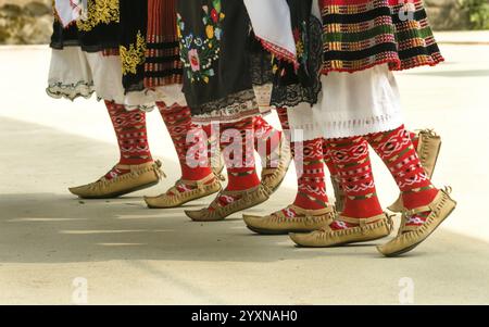 Bulgarische Folklore. Mädchen tanzen Volkstanz. Menschen in traditionellen Kostümen tanzen bulgarische Volkstänze. Nahaufnahme der weiblichen Beine mit traditionellem Sho Stockfoto