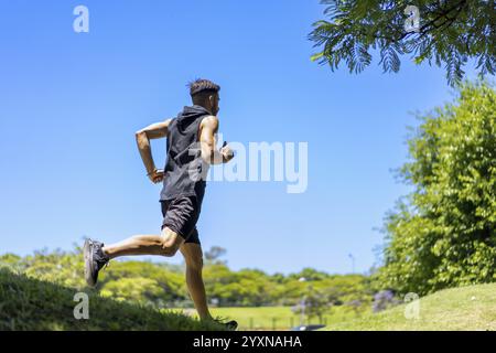 Ein Mann, der auf hügeligen Wegen in einem ruhigen Naturpark joggt Stockfoto