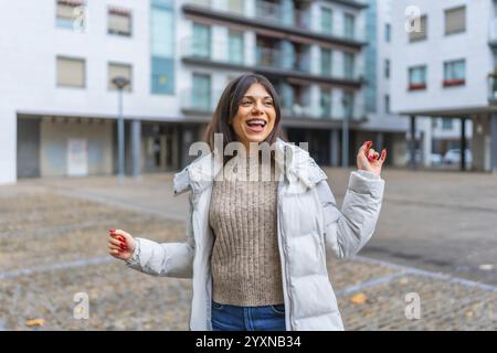 Glückliche Schönheitsfrau mit Jacke und warmer Kleidung, die in der Stadt tanzt Stockfoto