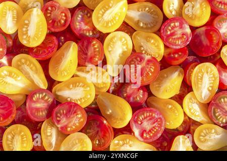 Frische Hälften mexikanischer Kirschtomaten. In Scheiben geschnittene gelbe und rote Kirschtomaten.Hintergrund von vielen bunten Kirschtomaten. Kirschtomaten Draufsicht. Stockfoto