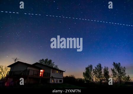 Der Durchgang der SpaceX G2-9 Starlink-Gruppe mit der Satellitenkette über einem Haus. Stockfoto