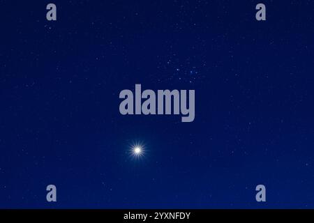Eine enge Passage der Venus durch den Sternhaufen Plejaden, inmitten der tiefblauen Dämmerung. Stockfoto