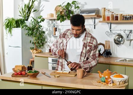Ein hübscher junger Mann verteilt Marmelade auf Toast, während er einen hellen Morgen in der Küche genießt. Stockfoto