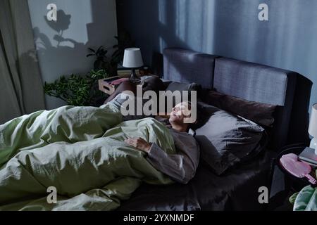 Hochwinkelaufnahme eines zweirassigen Paares, das in einem bequemen Bett leicht schlafen kann, das nachts vom Mondlicht erleuchtet wird Stockfoto