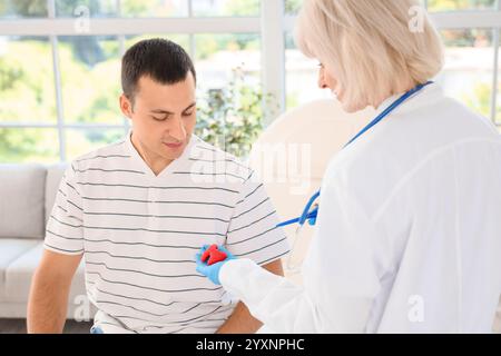Endokrinologin zeigt Schilddrüsenmodell bei männlichem Patienten in der Klinik Stockfoto