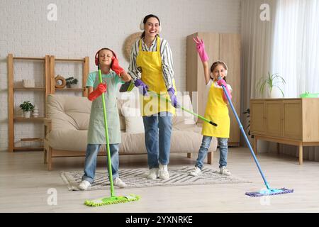 Mutter und ihre Kinder in Kopfhörern haben Spaß beim Reinigen zu Hause Stockfoto