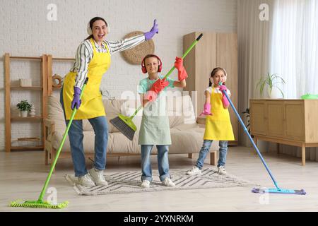 Mutter und ihre Kinder in Kopfhörern haben Spaß beim Reinigen zu Hause Stockfoto