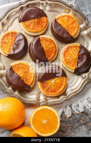 Shortbread-Kekse mit karamelisierter Orange, bedeckt mit Schokoladenglasur, Nahaufnahme auf einem Teller auf dem Tisch. Vertikale Draufsicht von oben Stockfoto