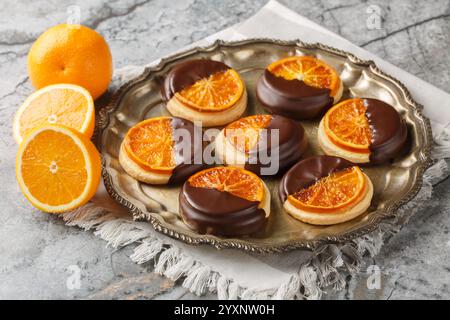 Süße leckere Kekse mit kandierter Orange und Schokoladenglasur in Nahaufnahme auf einem Teller auf dem Tisch. Horizontal Stockfoto