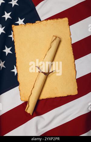 Schließen Sie ein leeres altes altes altes gelbes Papierblatt, und scrollen Sie auf einem mit Baumwolle gestickten Hintergrund der US-Nationalflagge, Symbol der amerikanischen Geschichte, hoch oben Stockfoto