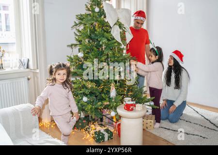Die Familie genießt eine schöne Zeit in der Nähe des geschmückten Weihnachtsbaums. Die Kinder packen Geschenke aus, spielen und genießen die festliche Atmosphäre des Weihnachtsfestes Stockfoto