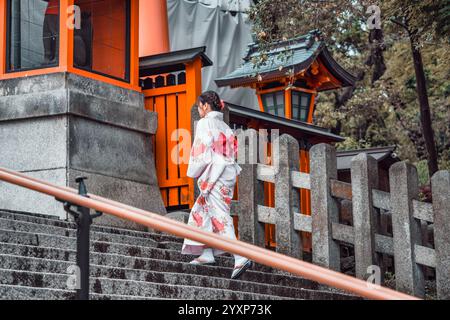 Frau mit traditionellem japanischem Yukata-Kimono und Spaziergang auf den Stufen am Fushimi Inari-Schrein in Kyoto. Stockfoto