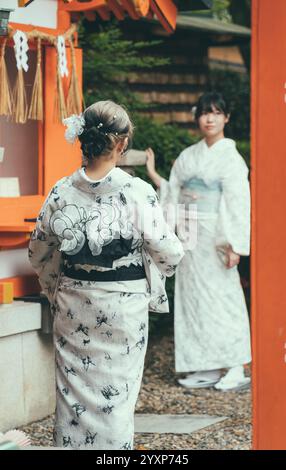 Kyoto, Japan - 05.07.2024: Zwei asiatische Frauen tragen im Fushimi Inari-Schrein einen traditionellen japanischen Yukata-Kimono. Stockfoto