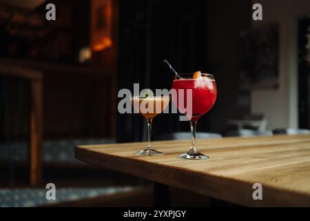 Zwei farbenfrohe Sommercocktails in Gläsern auf Holztisch. Auswahl an frischen Sommergetränken. Rote Sangria-Cocktails, Orangenpunsch-Cocktail. Stockfoto