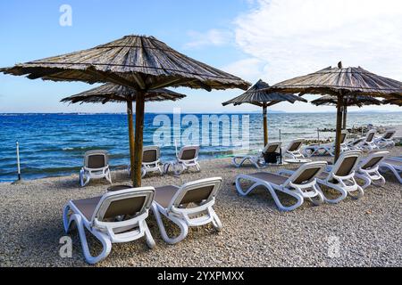 Leeres Strandcafé ohne Besucher nach Ende der Saison, Schilfsonnenschirme, leere Liegen, Adria, Kroatien Stockfoto