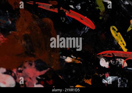 Mehrfarbige Farbstriche auf schwarzem Kunststoff als Hintergrund, Pinselstriche, Tapete Stockfoto