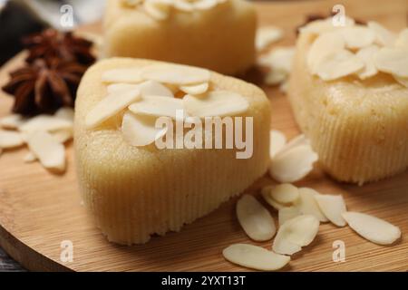 Stücke von köstlicher süßer Grießhalva mit Mandelflocken auf Holzbrett, Nahaufnahme Stockfoto