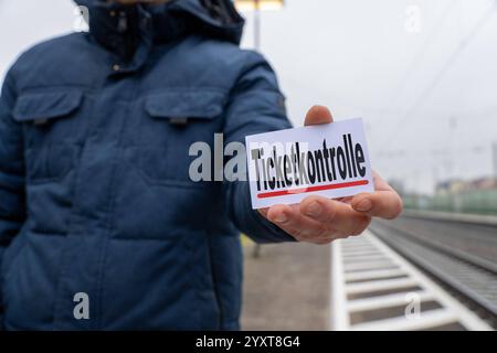 Bayern, Deutschland - 17. Dezember 2024: Eine Person hält ein Schild mit dem Text Ticket Control. Symbolisches Bild für die Kontrolle des öffentlichen Nahverkehrs, die Fahrpreisumgehung und die Arbeit der Fahrkarteninspektoren. FOTOMONTAGE *** eine Person hält ein Schild mit dem Text Ticketkontrolle. Symbolbild für Kontrollen im öffentlichen Nahverkehr, Schwarzfahren und die Arbeit von Kontrolleuren. FOTOMONTAGE Stockfoto