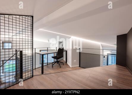 Stilvolles Büro-Loft mit modernem ergonomischem Stuhl, großem Holzboden und schlanken minimalistischen Designelementen, perfekt für kreative Profis Stockfoto