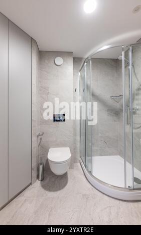 Modernes Bad mit verglaster Dusche, elegantem weißem Waschbecken, grauen gefliesten Wänden und modernen Annehmlichkeiten in einem ordentlichen und minimalistischen Ambiente Stockfoto