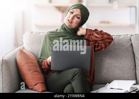 Reife Muslimische Geschäftsfrau, Die Den Hals Berührt Und Schmerzen Mit Einem Laptop In Der Halle Hat Stockfoto