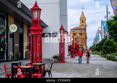 Die Leute laufen entlang des roten Zauns auf dem Quay St Gehweg, der Hafenpromenade von Auckland, Downtown Terminal Ferry Gebäude, entworfen von Alex Wiseman, Neuseeland Stockfoto