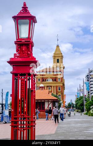 Die Leute laufen entlang des roten Zauns auf dem Quay St Gehweg, der Hafenpromenade von Auckland, Downtown Terminal Ferry Gebäude, entworfen von Alex Wiseman, Neuseeland Stockfoto