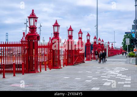 Die Leute laufen entlang des roten Zauns auf dem Quay St Sidewalk, Queens Wharf, Auckland Harbour Front, Neuseeland Stockfoto