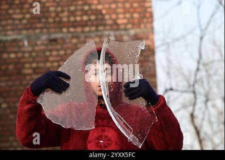 Srinagar, Indien. Dezember 2024. SRINAGAR, INDIEN – 17. DEZEMBER: Ein Junge zeigt ein Stück gefrorenes Eis an einem kalten Wintermorgen am 17. Dezember 2024 in Srinagar, Indien. Kaltwelle Griffe Kaschmir, da Srinagar die minimale Temperatur bei minus 5,3 Grad Celsius aufzeichnet. (Foto: Waseem Andrabi/Hindustan Times/SIPA USA) Credit: SIPA USA/Alamy Live News Stockfoto