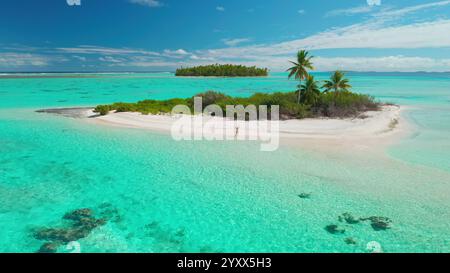 Aus der Vogelperspektive einer Frau, die ihre Arme hebt, an einem unberührten weißen Sandstrand einer tropischen Insel, umgeben von türkisfarbenem Wasser Stockfoto