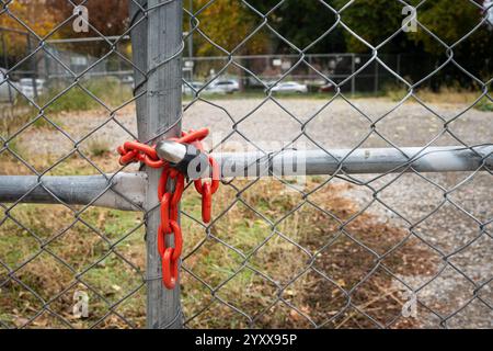 Ein Vorhängeschloss und eine rote Kette an einem Maschendrahtzaun um ein leeres Grundstück in der Innenstadt von Sacramento Stockfoto